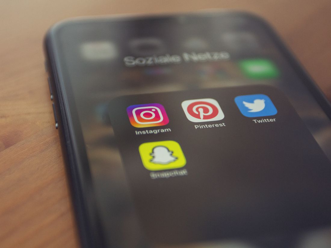 A smartphone showing a clinic ad on Facebook and Instagram with a treatment photo, a Book Now button, and visible targeting indicators for location and patient demographics, styled with ClinicsRise navy and teal accents