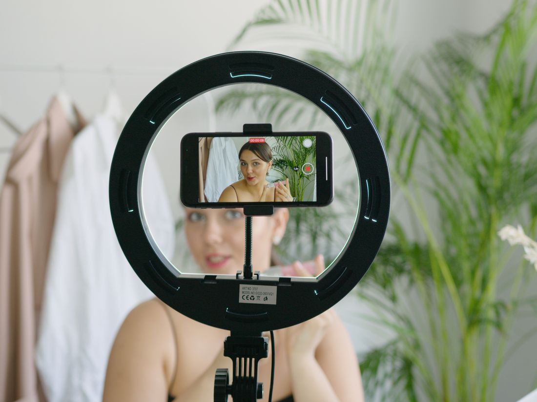 A smartphone showing a TikTok-style clinic video of a before and after dental transformation with hearts, comments, and shares visible, and arrows pointing outward to new viewers, styled with ClinicsRise navy and teal accents