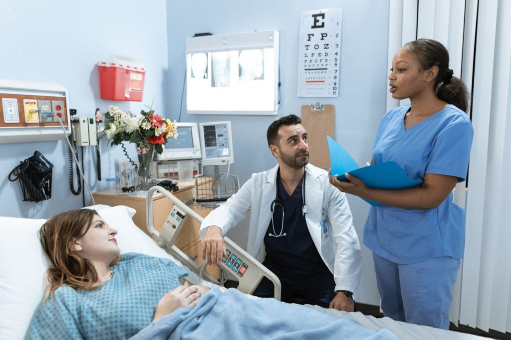 A doctor and nurse speaking with a patient in a clinic room