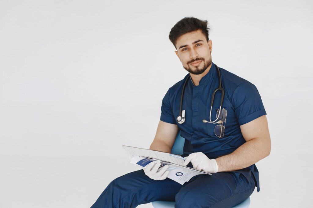 A young doctor in blue scrubs holding patient paperwork