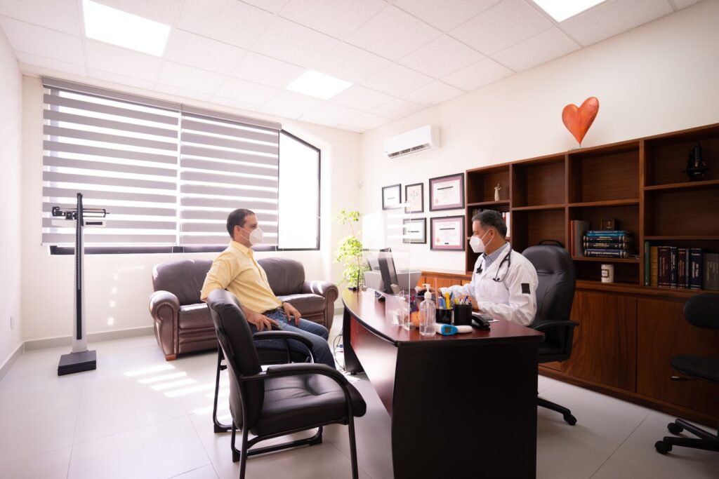 Doctor and patient talking across a desk in a clinic consultation room