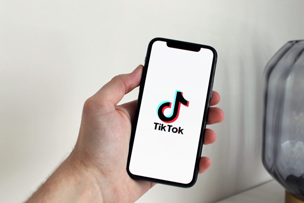 Hand holding a phone with the TikTok app open, representing TikTok marketing for clinics
